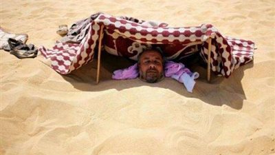 شاهد.. كيفية علاج الروماتيزم بالدفن في الرمال(صور)