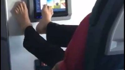 راكب يستخدم شاشة التحكم بقدميه العاريتين في الطائرة (فيديو)